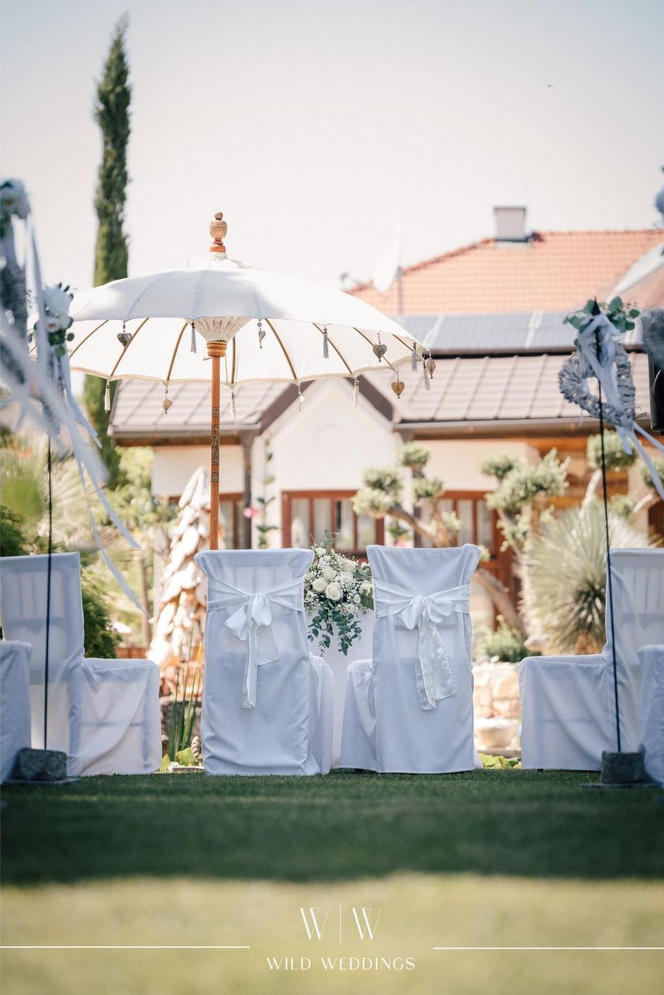 Weiße Stühle und ein Schirm im Garten des Gasthaus Hirschbeck bei einer Hochzeit